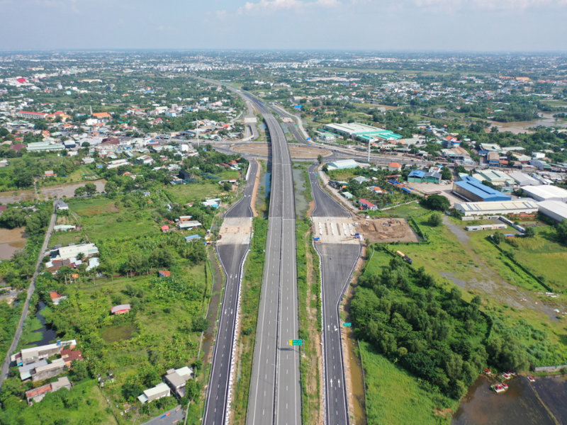 Aerial view of a modern highway cutting through green fields and urban areas in Long Thanh, Dong Nai.