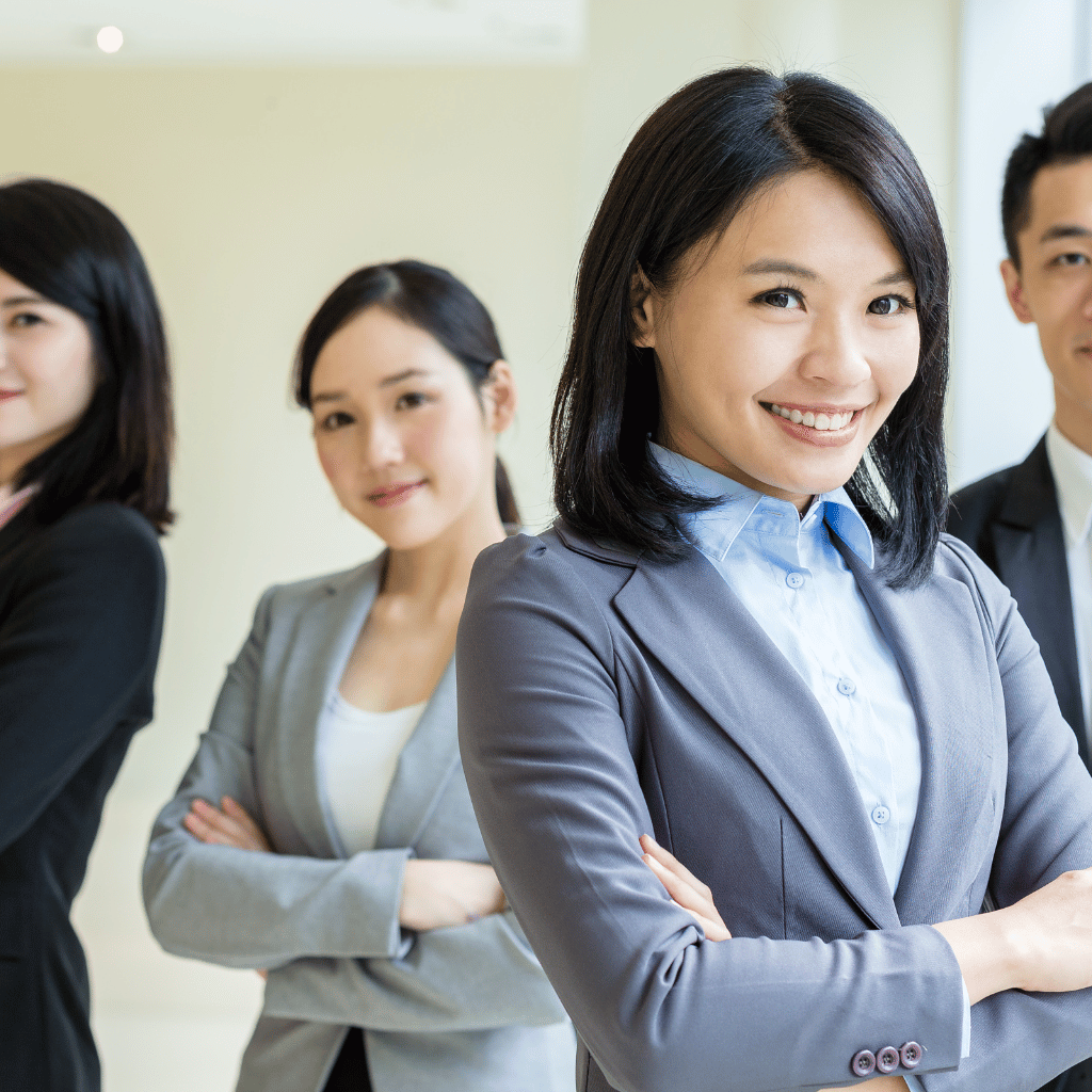 A group of migration and investment link staffs in business attire standing with arms crossed, symbolizing confidence and support in migration services.