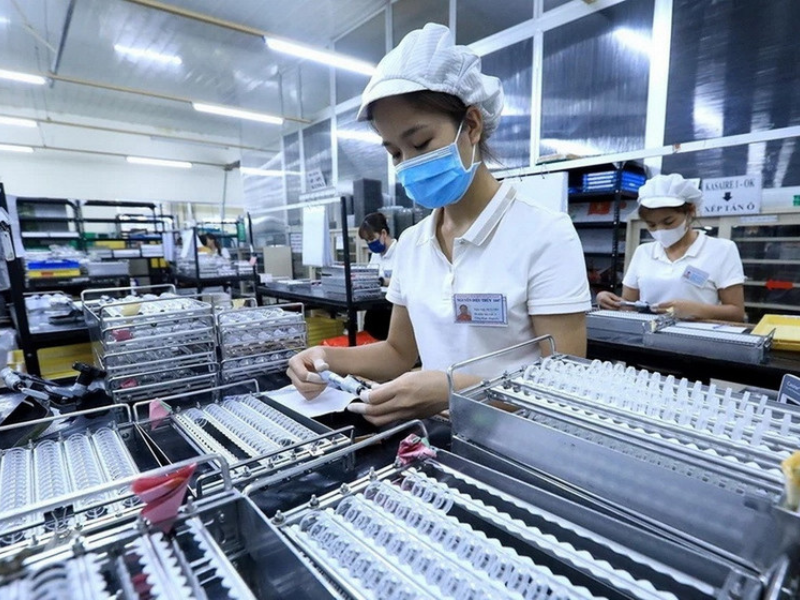 Workers in a Vietnam FDI manufacturing facility handling precision components, showcasing industrial growth.