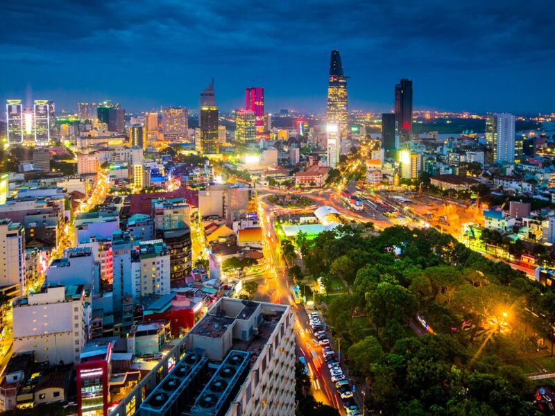 Vibrant Vietnam real estate investment scene: Night skyline of Ho Chi Minh City with illuminated skyscrapers and bustling streets.