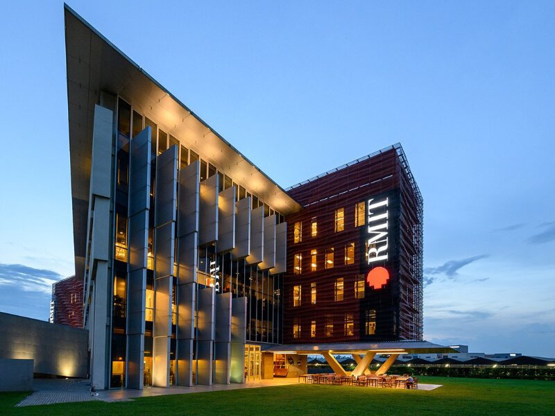 Vietnam Education Investment showcased in RMIT Vietnam's modern campus building illuminated at dusk with green lawns.