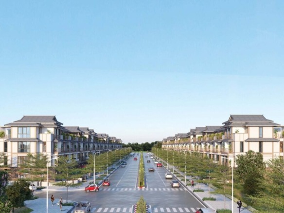 Aerial view of modern commercial housing development in HCMC featuring 74 pilot areas with traditional tiled roofs, tree-lined boulevards, and pedestrian pathways under a clear blue sky.