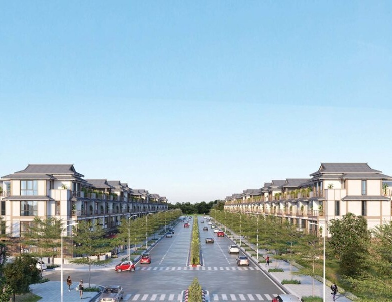 Aerial view of modern commercial housing development in HCMC featuring 74 pilot areas with traditional tiled roofs, tree-lined boulevards, and pedestrian pathways under a clear blue sky.
