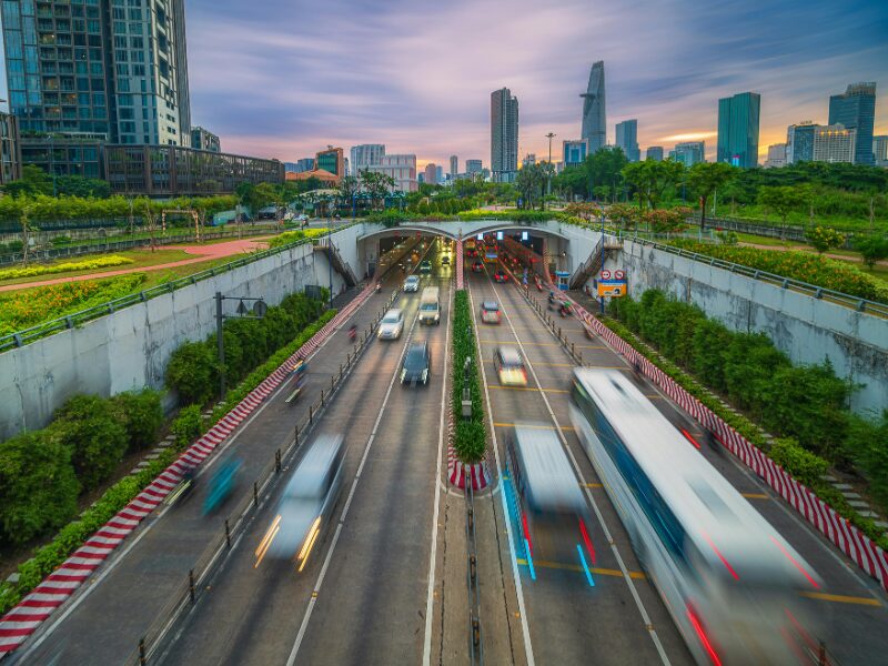 Aerial view of modern urban infrastructure in Vietnam showcasing high-rise buildings, green overpasses, and bustling traffic at sunset, symbolizing the surge in Vietnam real estate foreign investment and economic development.