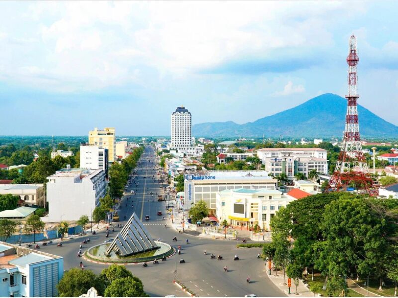 Aerial view of Tay Ninh cityscape showcasing modern buildings, communication tower, and mountainous backdrop, highlighting Tay Ninh Investment Promotion opportunities.