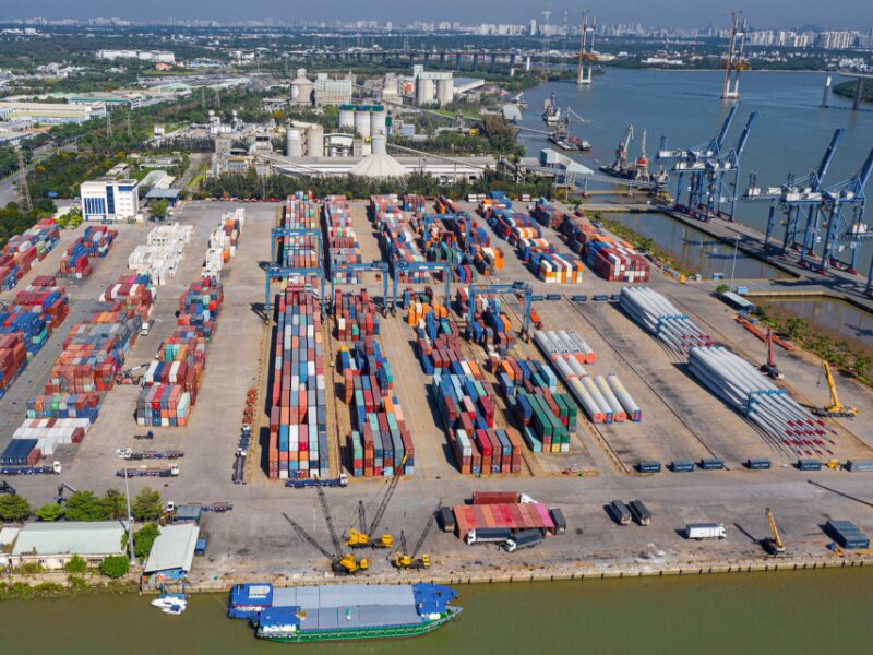 Aerial view of Vietnam industrial real estate at a bustling seaport with stacked containers and cranes enhancing logistics efficiency.