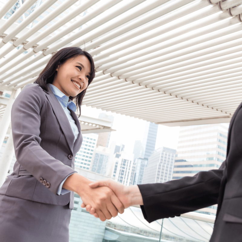 Two professionals shaking hands under a modern architectural structure for migration consultation.
