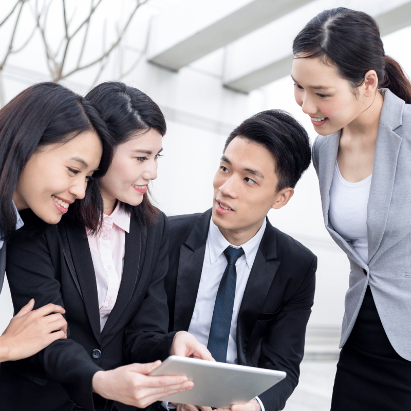 A group of business professionals collaborating and reviewing a tablet on a rooftop, symbolizing teamwork in developing a real estate investment strategy.